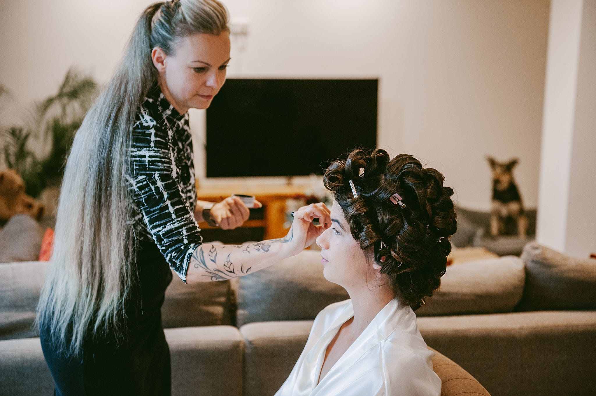 Visagistin Franziska Bleher trägt Rouge bei einer Braut mit Lockenwicklern auf