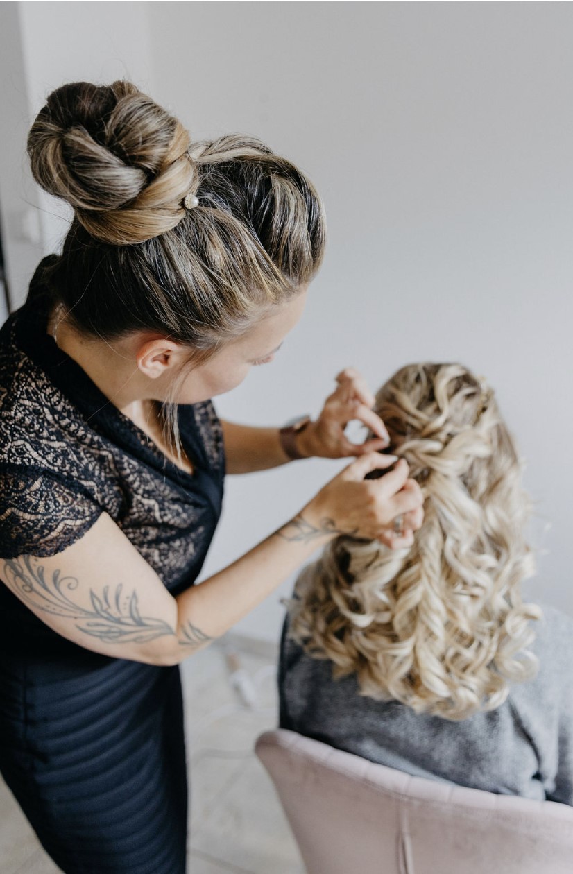 Friseurmeisterin Franziska Bleher steckt blonde Locken zu einer halboffenen Brautfrisur