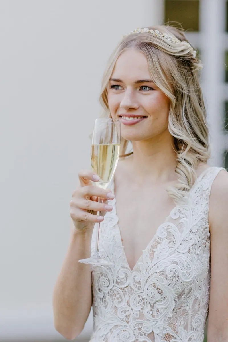 Braut mit Sekt und halboffener Brautfrisur