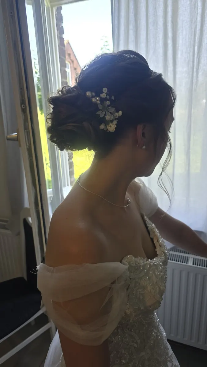 Hochsteckfrisur mit Blüten zum schulterfreien Brautkleid